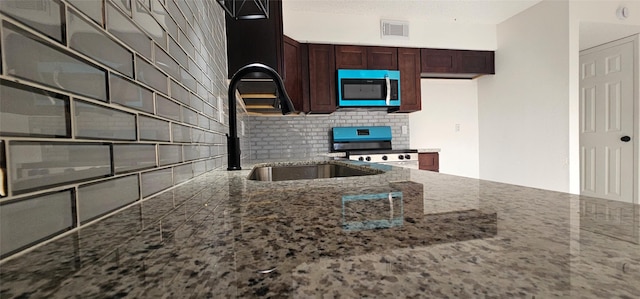 12819 Carvel Ln, Houston, TX 77072 - kitchen with stainless steel microwave, stove, dark stone countertops, tasteful backsplash, and a sink