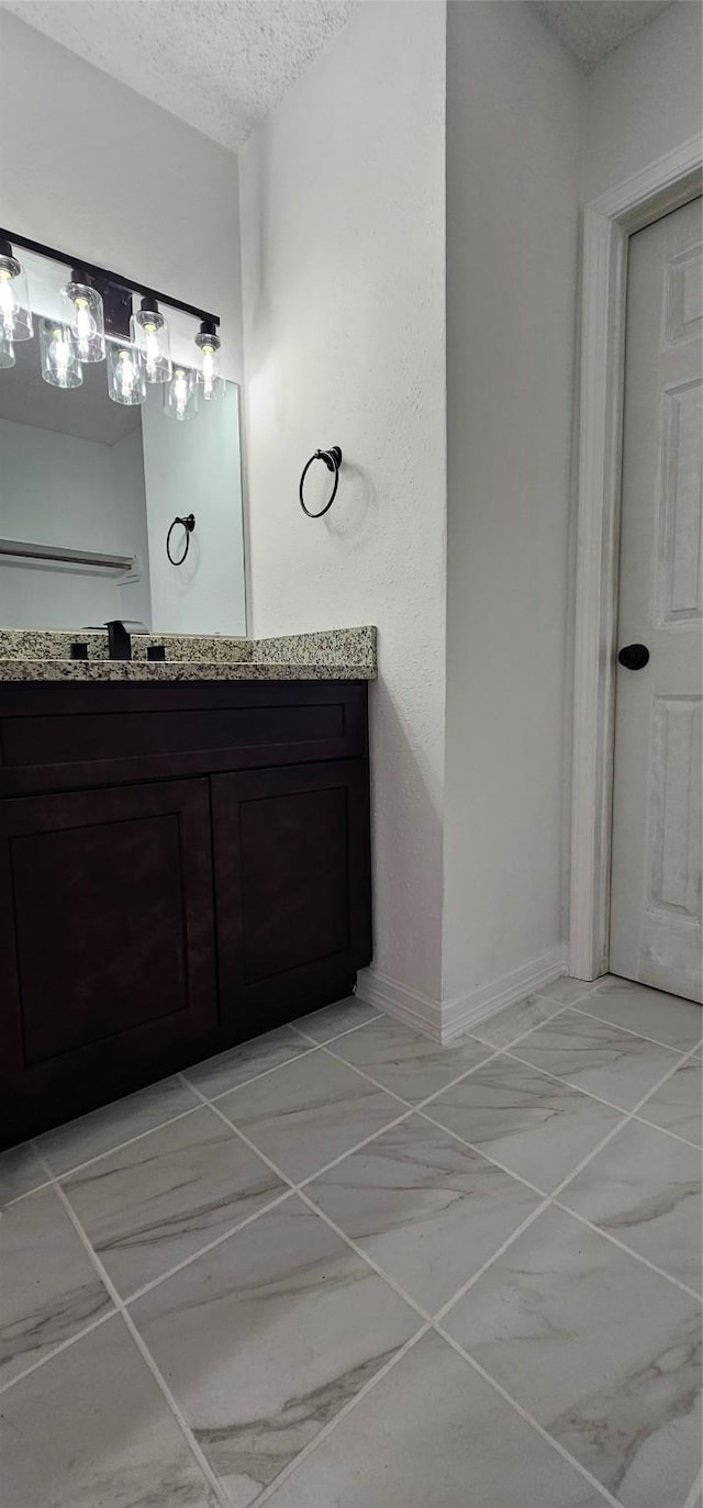 12819 Carvel Ln, Houston, TX 77072 - bathroom with marble finish floors, vanity, a textured ceiling, and baseboards