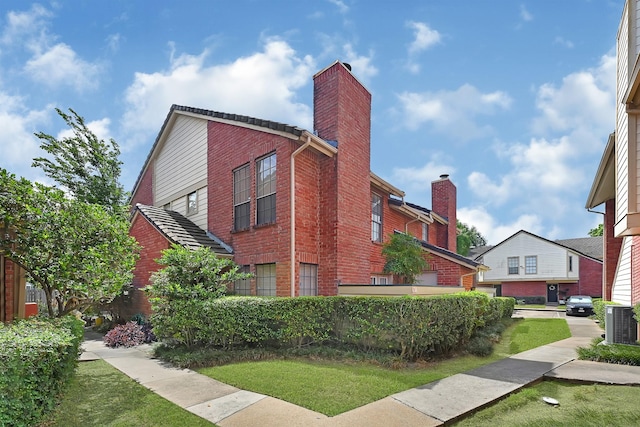 2211 S Kirkwood Rd Unit 26, Houston, TX 77077 - view of property exterior with brick siding, a chimney, cooling unit, and a lawn