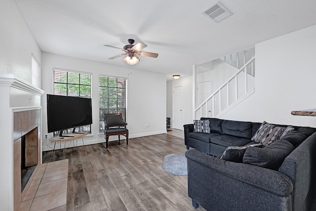 2211 S Kirkwood Rd Unit 26, Houston, TX 77077 - living room featuring stairs, a tiled fireplace, wood finished floors, and a ceiling fan