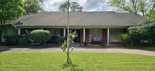 1 Lazy Ln, Bay City, TX 77414 - view of front of home featuring a front lawn, covered porch, roof with shingles, and brick siding