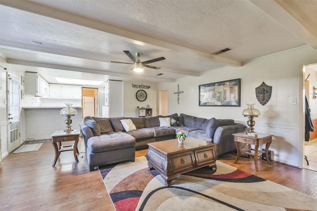 1805 Twila Ln, Conroe, TX 77301 - living room featuring light wood-type flooring, beamed ceiling, a textured ceiling, and ceiling fan