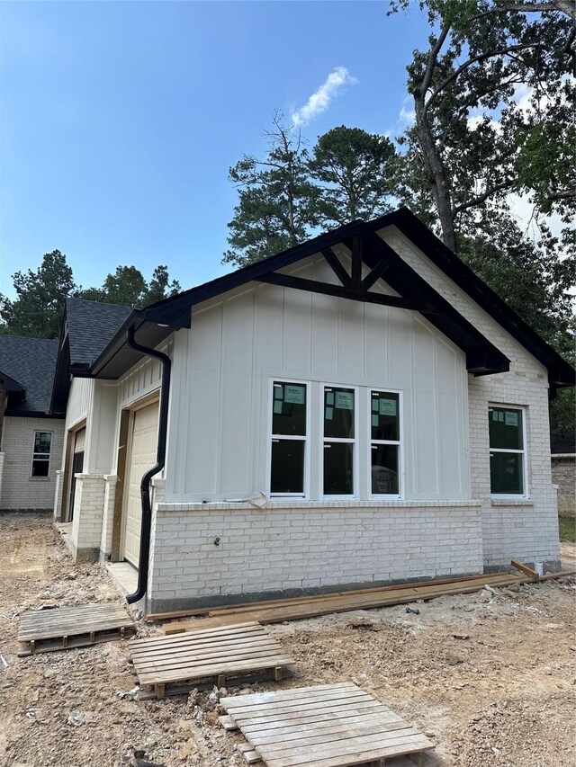 2439 Centurian Cir, Roman Forest, TX 77357 - view of side of home featuring board and batten siding, brick siding, an attached garage, and roof with shingles