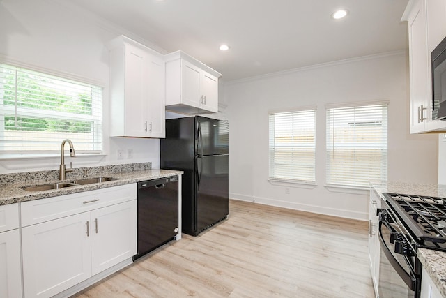 7974 Fowlie St, Houston, TX 77028 - kitchen featuring black appliances, a sink, ornamental molding, light wood-style flooring, and white cabinetry