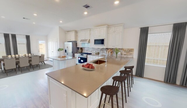 5210 Lake Trout Ln, Baytown, TX 77521 - kitchen with appliances with stainless steel finishes, a kitchen island, backsplash, a sink, and vaulted ceiling