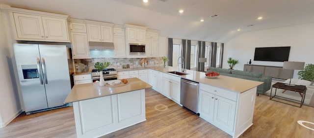 5210 Lake Trout Ln, Baytown, TX 77521 - kitchen with stainless steel appliances, a sink, open floor plan, lofted ceiling, and a peninsula