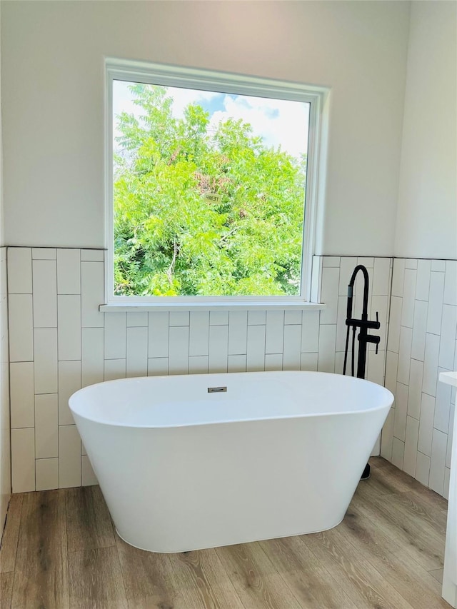 7107 Foster St Unit A, Houston, TX 77021 - bathroom with tile walls, a freestanding bath, wood finished floors, and a wainscoted wall