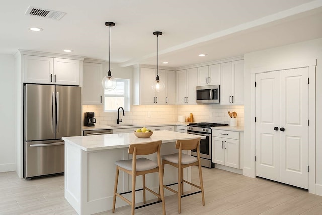 7107 Foster St Unit A, Houston, TX 77021 - kitchen featuring appliances with stainless steel finishes, backsplash, light countertops, a center island, and decorative light fixtures