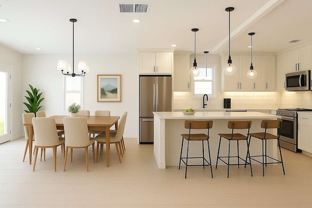 7107 Foster St Unit A, Houston, TX 77021 - kitchen with appliances with stainless steel finishes, backsplash, a center island, a breakfast bar area, and a chandelier