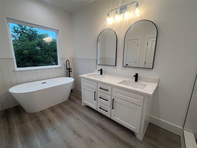 7107 Foster St Unit A, Houston, TX 77021 - bathroom featuring tile walls, wood finished floors, double vanity, a freestanding tub, and a wainscoted wall