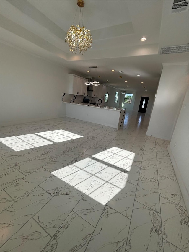 6197 Rd 5503, Cleveland, TX 77327 - unfurnished living room featuring a chandelier, a raised ceiling, recessed lighting, light marble finish flooring, and a sink