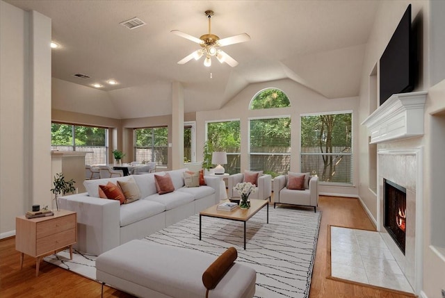 30 Teak Mill Pl, The Woodlands, TX 77382 - living area with light wood-type flooring, vaulted ceiling, a fireplace with flush hearth, ceiling fan, and baseboards