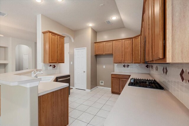 30 Teak Mill Pl, The Woodlands, TX 77382 - kitchen with a sink, gas stovetop, a peninsula, brown cabinetry, and tasteful backsplash