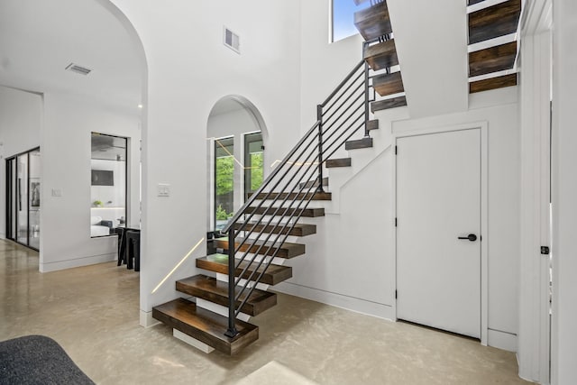11736 Canyon Ct, Conroe, TX 77385 - stairway featuring arched walkways, finished concrete floors, and a towering ceiling