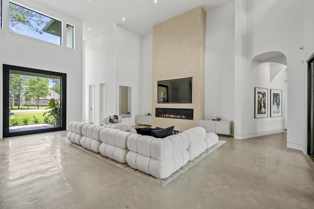 11736 Canyon Ct, Conroe, TX 77385 - living room with a towering ceiling, finished concrete floors, a lit fireplace, arched walkways, and baseboards