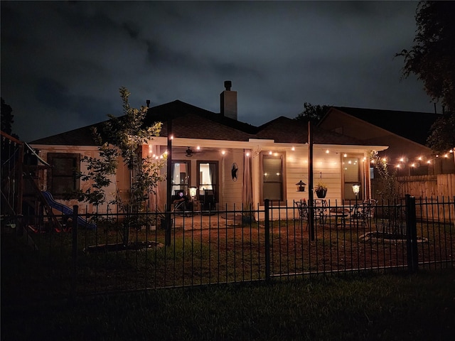 723 Hinsdale, Magnolia, TX 77354 - back of house at twilight featuring a fenced front yard and a chimney