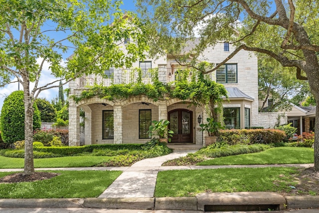 3019 Sunset Blvd, Houston, TX 77005 - view of front of home featuring stone siding, french doors, a balcony, a front lawn, and a standing seam roof