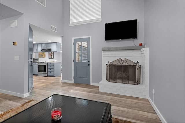 4220 Kenbrook Dr, Nacogdoches, TX 75965 - living area with baseboards, light wood-style floors, a fireplace, and a towering ceiling