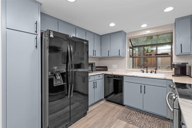 4220 Kenbrook Dr, Nacogdoches, TX 75965 - kitchen featuring black appliances, a sink, light wood-style flooring, gray cabinets, and decorative backsplash