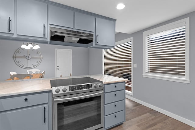 4220 Kenbrook Dr, Nacogdoches, TX 75965 - kitchen with electric stove, gray cabinets, under cabinet range hood, wood finished floors, and baseboards