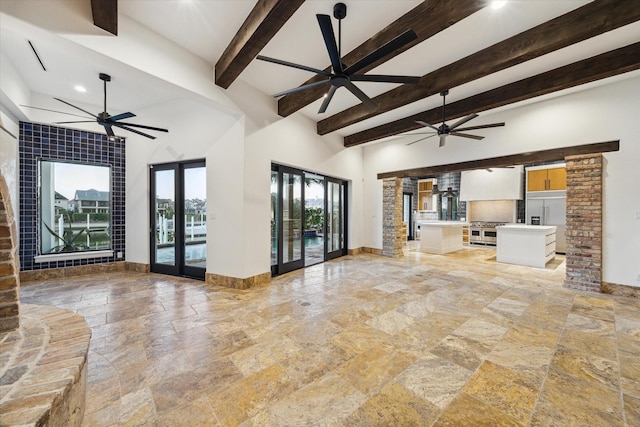 721 Harborside Way, League City, TX 77565 - unfurnished living room with stone tile floors, ceiling fan, baseboards, beamed ceiling, and a high ceiling