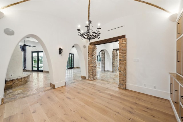 721 Harborside Way, League City, TX 77565 - unfurnished dining area featuring arched walkways, light wood-type flooring, a chandelier, high vaulted ceiling, and baseboards