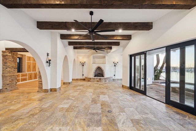 721 Harborside Way, League City, TX 77565 - unfurnished living room with beamed ceiling, ceiling fan, a brick fireplace, baseboards, and arched walkways