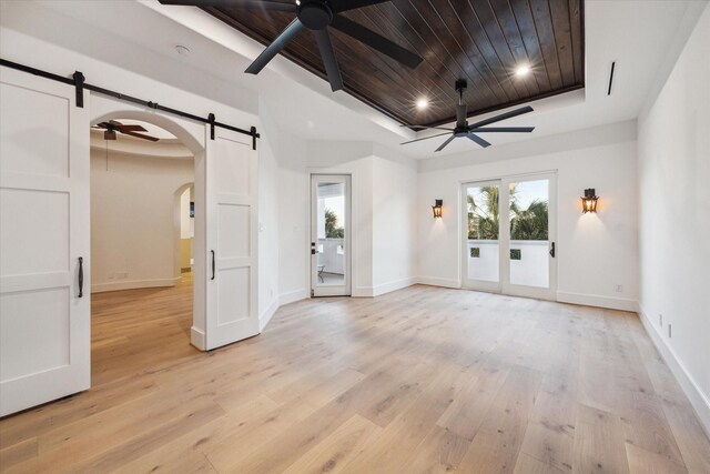 721 Harborside Way, League City, TX 77565 - spare room featuring a barn door, a ceiling fan, arched walkways, a tray ceiling, and wooden ceiling