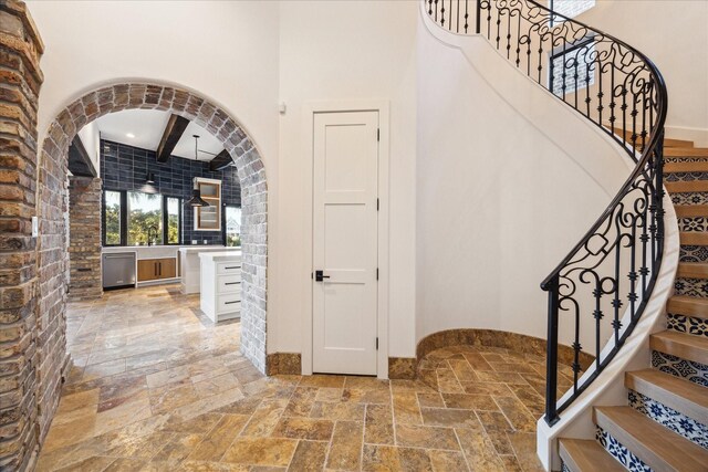 721 Harborside Way, League City, TX 77565 - staircase with stone tile flooring, baseboards, arched walkways, a towering ceiling, and beamed ceiling