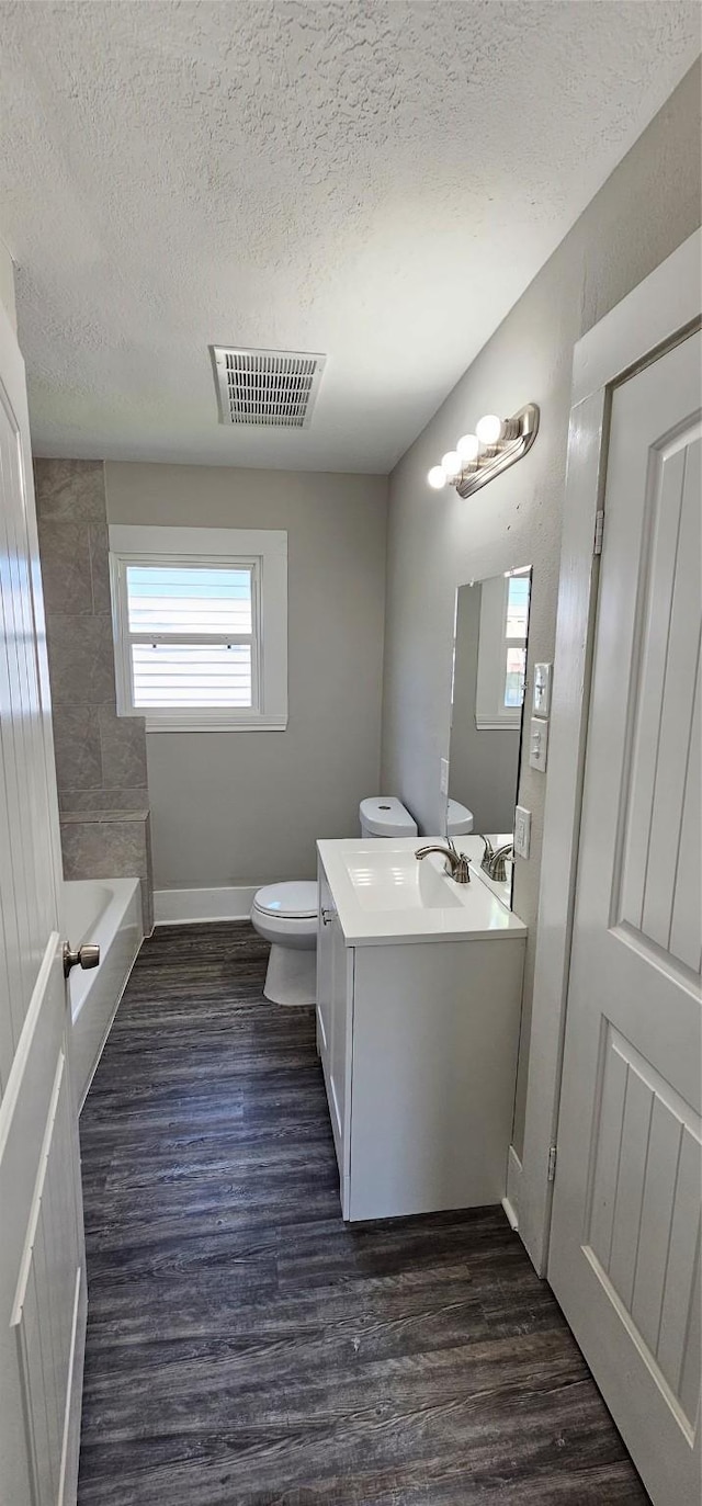215 San Jacinto St, Highlands, TX 77562 - full bathroom with a textured ceiling, vanity, toilet, a bathtub, and wood finished floors