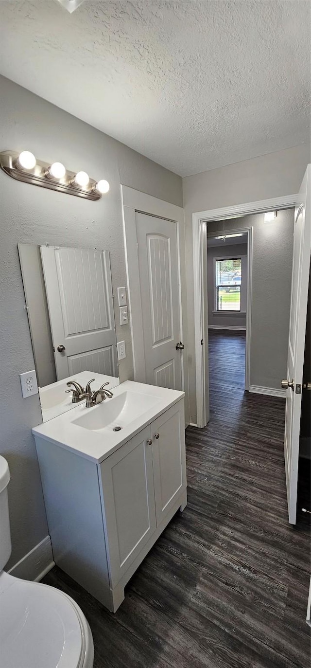 215 San Jacinto St, Highlands, TX 77562 - half bath featuring toilet, wood finished floors, vanity, a textured ceiling, and baseboards