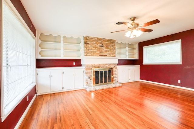 10134 Brinwood Dr, Houston, TX 77043 - unfurnished living room featuring light wood-style flooring, ceiling fan, baseboards, a fireplace, and built in shelves