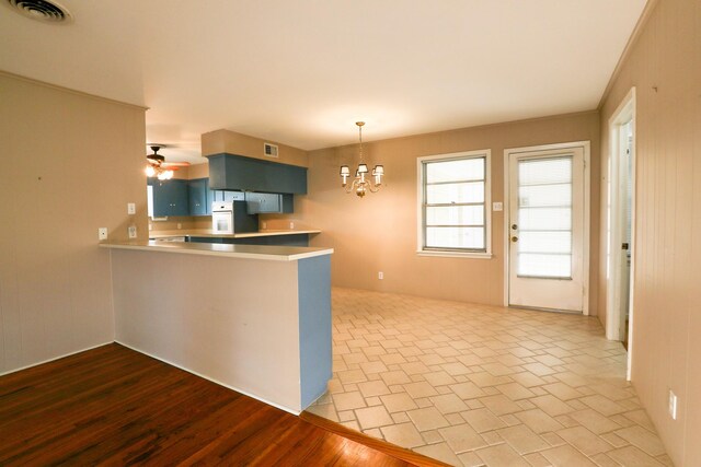 10134 Brinwood Dr, Houston, TX 77043 - kitchen featuring a chandelier, a peninsula, blue cabinets, pendant lighting, and a ceiling fan