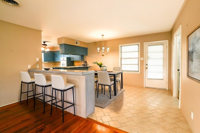 10134 Brinwood Dr, Houston, TX 77043 - kitchen with a chandelier, a kitchen breakfast bar, white oven, a peninsula, and decorative light fixtures