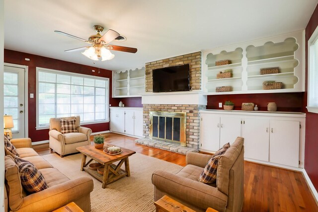 10134 Brinwood Dr, Houston, TX 77043 - living room featuring ceiling fan, light wood-type flooring, a brick fireplace, and baseboards