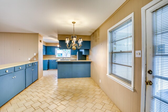 10134 Brinwood Dr, Houston, TX 77043 - kitchen with blue cabinetry, a chandelier, a sink, freestanding refrigerator, and a peninsula