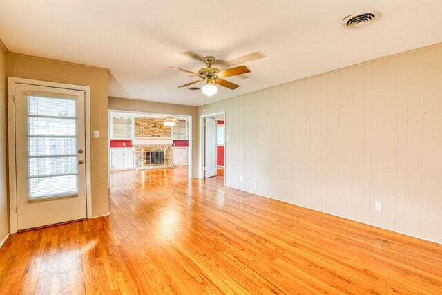 10134 Brinwood Dr, Houston, TX 77043 - unfurnished living room with a ceiling fan, light wood finished floors, plenty of natural light, and a brick fireplace