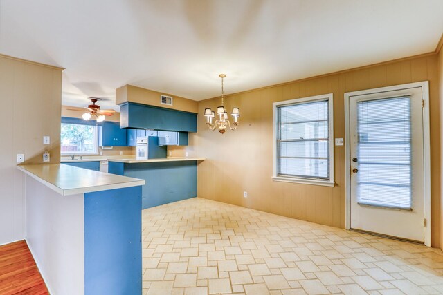10134 Brinwood Dr, Houston, TX 77043 - kitchen featuring blue cabinetry, a peninsula, a chandelier, wood walls, and light countertops