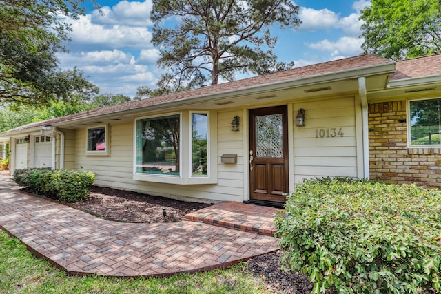 10134 Brinwood Dr, Houston, TX 77043 - doorway to property featuring an attached garage and brick siding