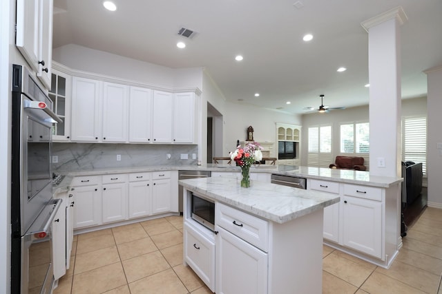 6 Lovenote Ct, The Woodlands, TX 77382 - kitchen with appliances with stainless steel finishes, a peninsula, light tile patterned floors, tasteful backsplash, and a kitchen island