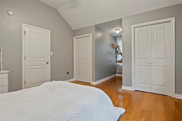 5318 E Plantation Oaks Dr, Arcola, TX 77583 - bedroom featuring multiple closets, light wood-type flooring, vaulted ceiling, and baseboards