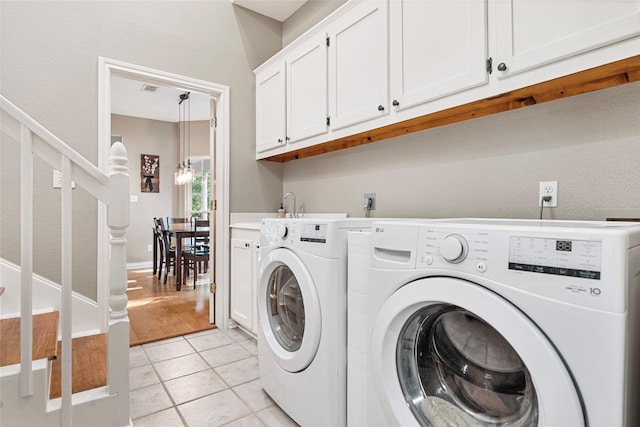 5318 E Plantation Oaks Dr, Arcola, TX 77583 - laundry room featuring independent washer and dryer, cabinet space, light tile patterned floors, and a chandelier