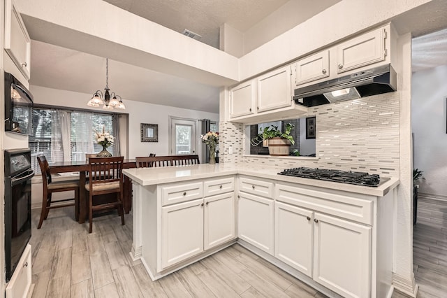 3106 Village Springs Ct, Houston, TX 77339 - kitchen with under cabinet range hood, black appliances, light countertops, and a chandelier