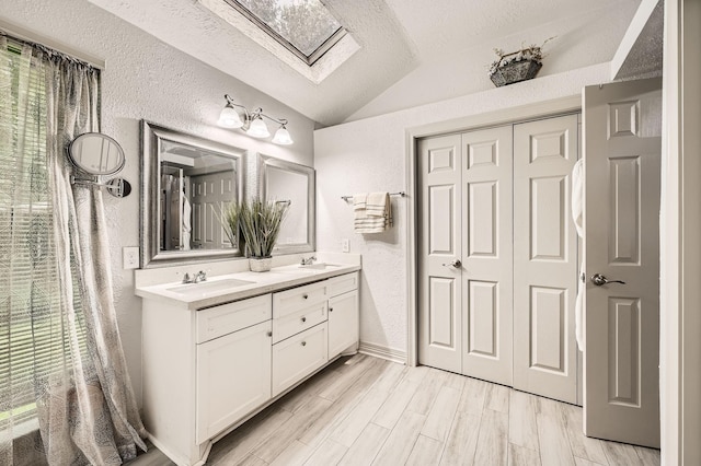 3106 Village Springs Ct, Houston, TX 77339 - full bath with lofted ceiling, double vanity, a textured wall, a textured ceiling, and a skylight