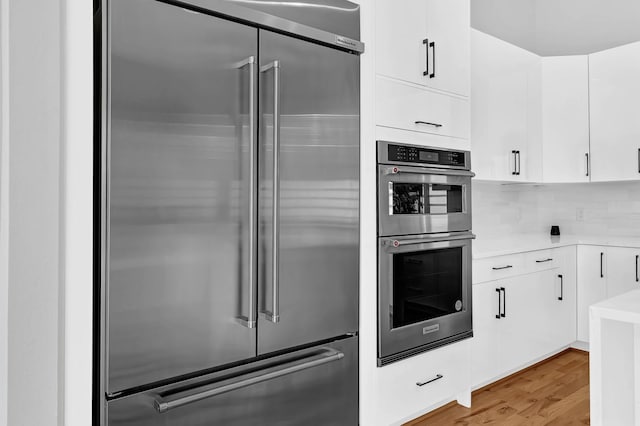 1505 Stuart St, Houston, TX 77004 - kitchen featuring appliances with stainless steel finishes, light countertops, white cabinets, and light wood-type flooring