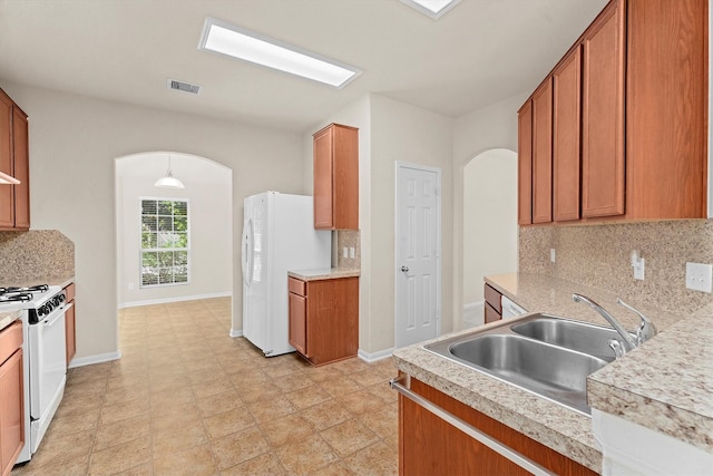 11410 Dahlia Dale Dr, Tomball, TX 77375 - kitchen with arched walkways, white appliances, a sink, tasteful backsplash, and baseboards