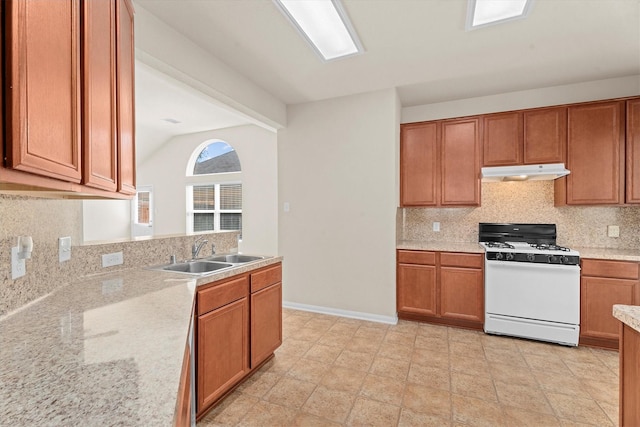 11410 Dahlia Dale Dr, Tomball, TX 77375 - kitchen with gas range gas stove, under cabinet range hood, a sink, tasteful backsplash, and brown cabinets