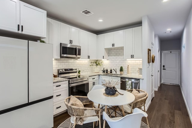 18823 Luminescent Ln, Spring, TX 77379 - kitchen featuring appliances with stainless steel finishes, a sink, decorative backsplash, white cabinets, and dark wood-style floors
