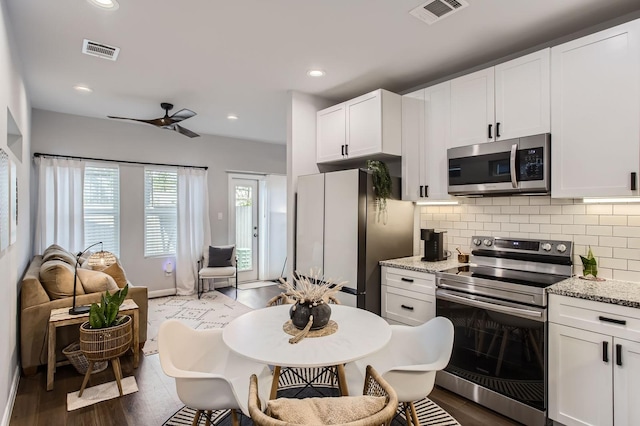 18823 Luminescent Ln, Spring, TX 77379 - kitchen featuring appliances with stainless steel finishes, ceiling fan, white cabinets, dark wood finished floors, and tasteful backsplash