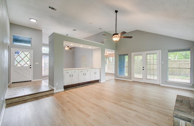 13215 Bunker Hill Dr, Willis, TX 77318 - unfurnished living room featuring ceiling fan, light wood-type flooring, a textured ceiling, healthy amount of natural light, and high vaulted ceiling
